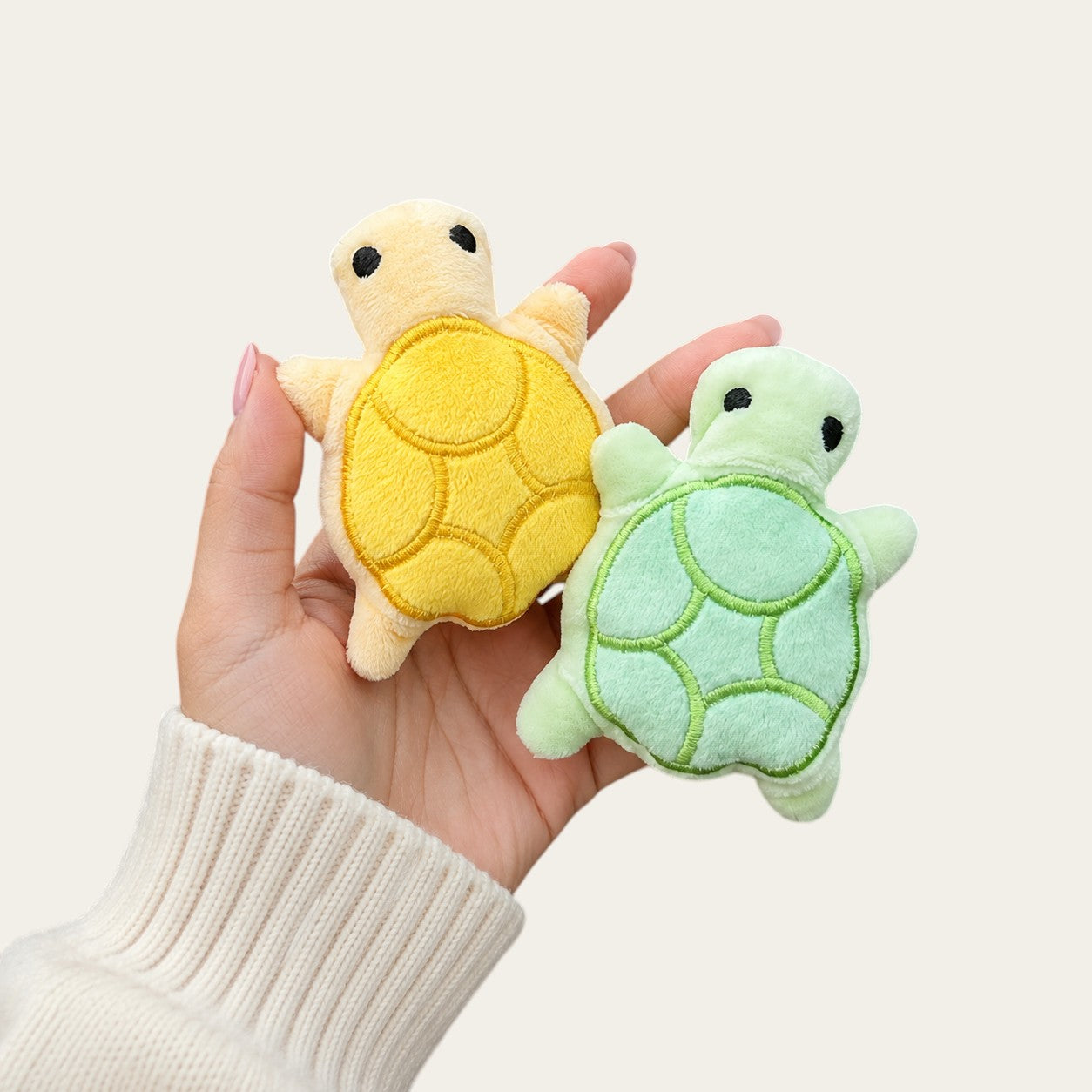 Main tenant deux mini tortues en peluche Pelorie jaune et vert clair, jouets doux pour chiots et petits chiens.