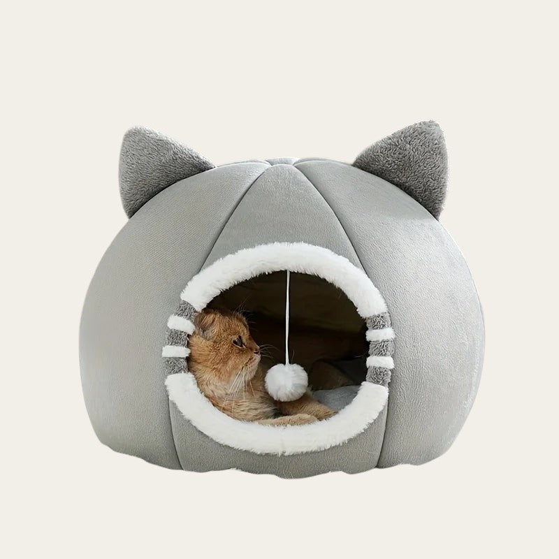 Niche pour chat Pelorie en forme de maisonnette grise avec oreilles et pompon suspendu pour un confort douillet