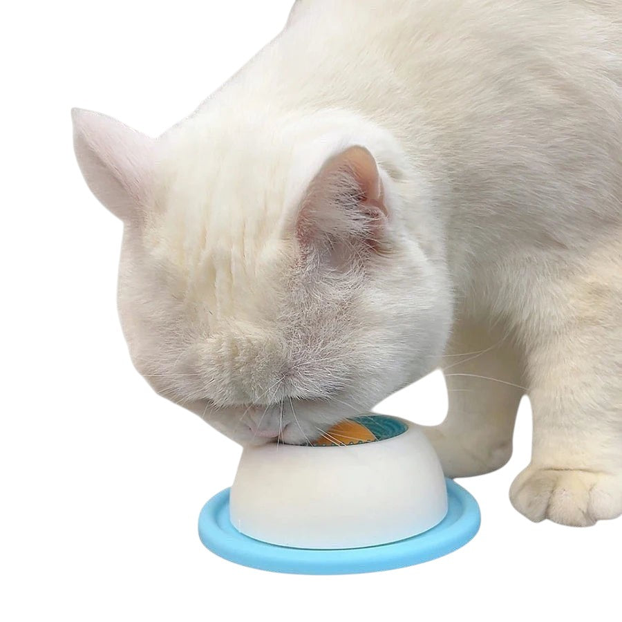 Chat blanc léchant de la nourriture sur un tapis à lécher Pelorie en silicone bleu et blanc avec ventouse